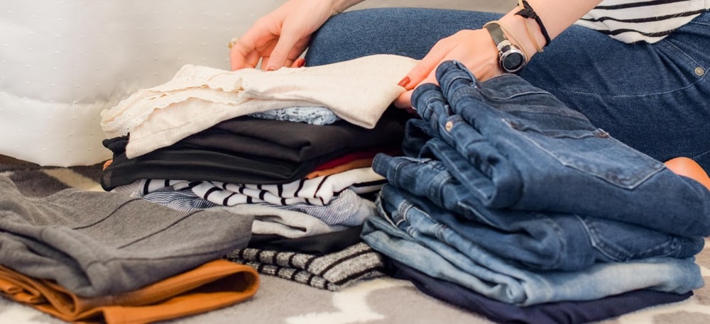 Stock photo of a person folding laundry and stacking it in piles by type